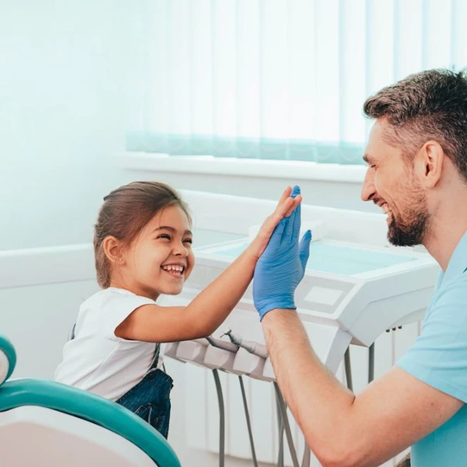 Young girl high-fiving her dentist after an appointment