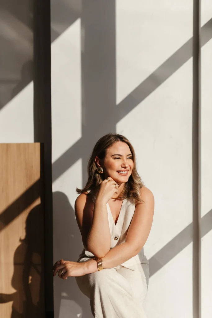 Smiling woman leaning against a sunlit wall