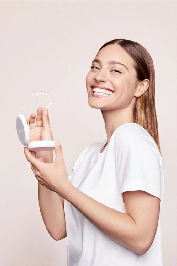 Woman smiling while holding a clear aligner and its case