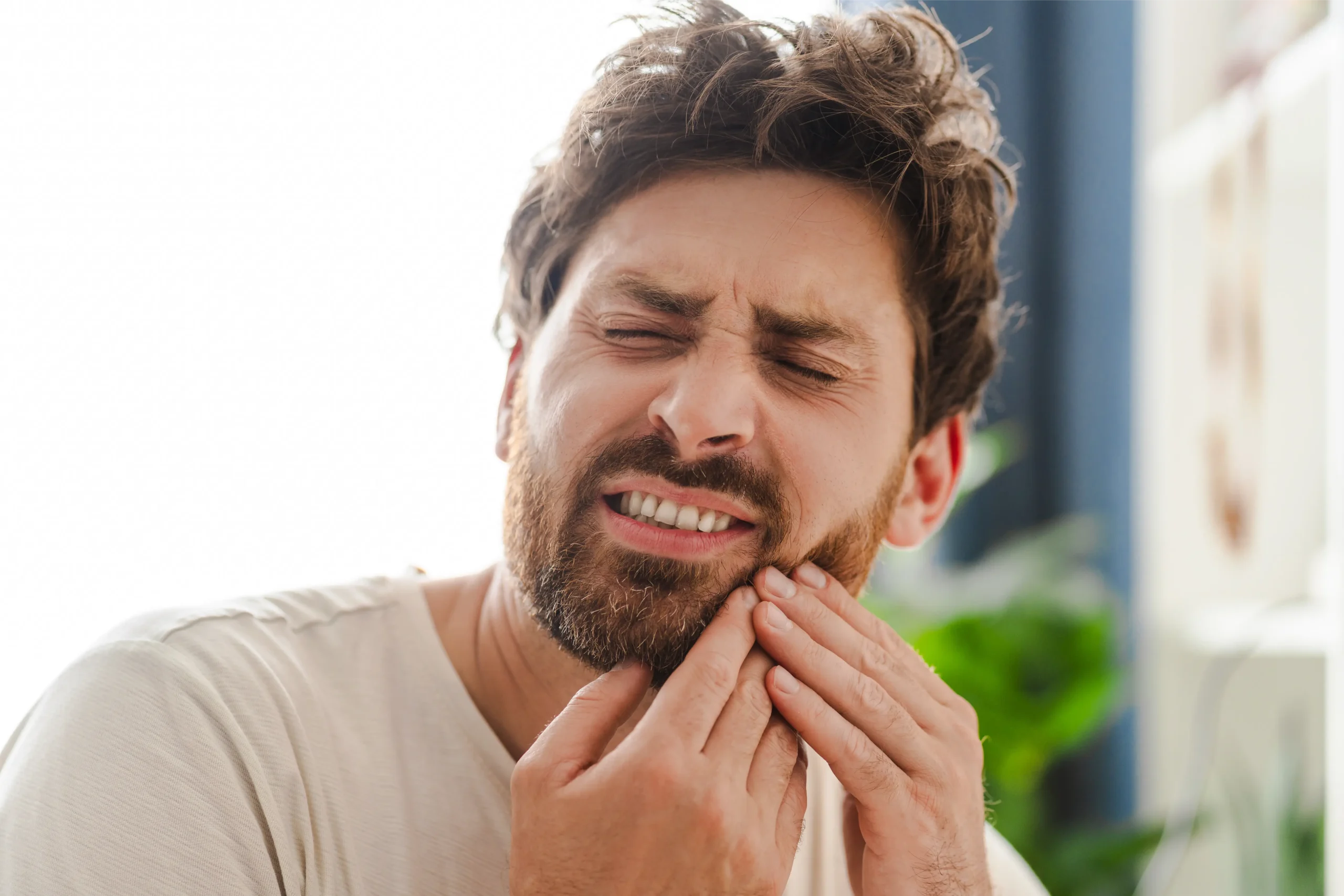 Man holding his jaw in tooth pain