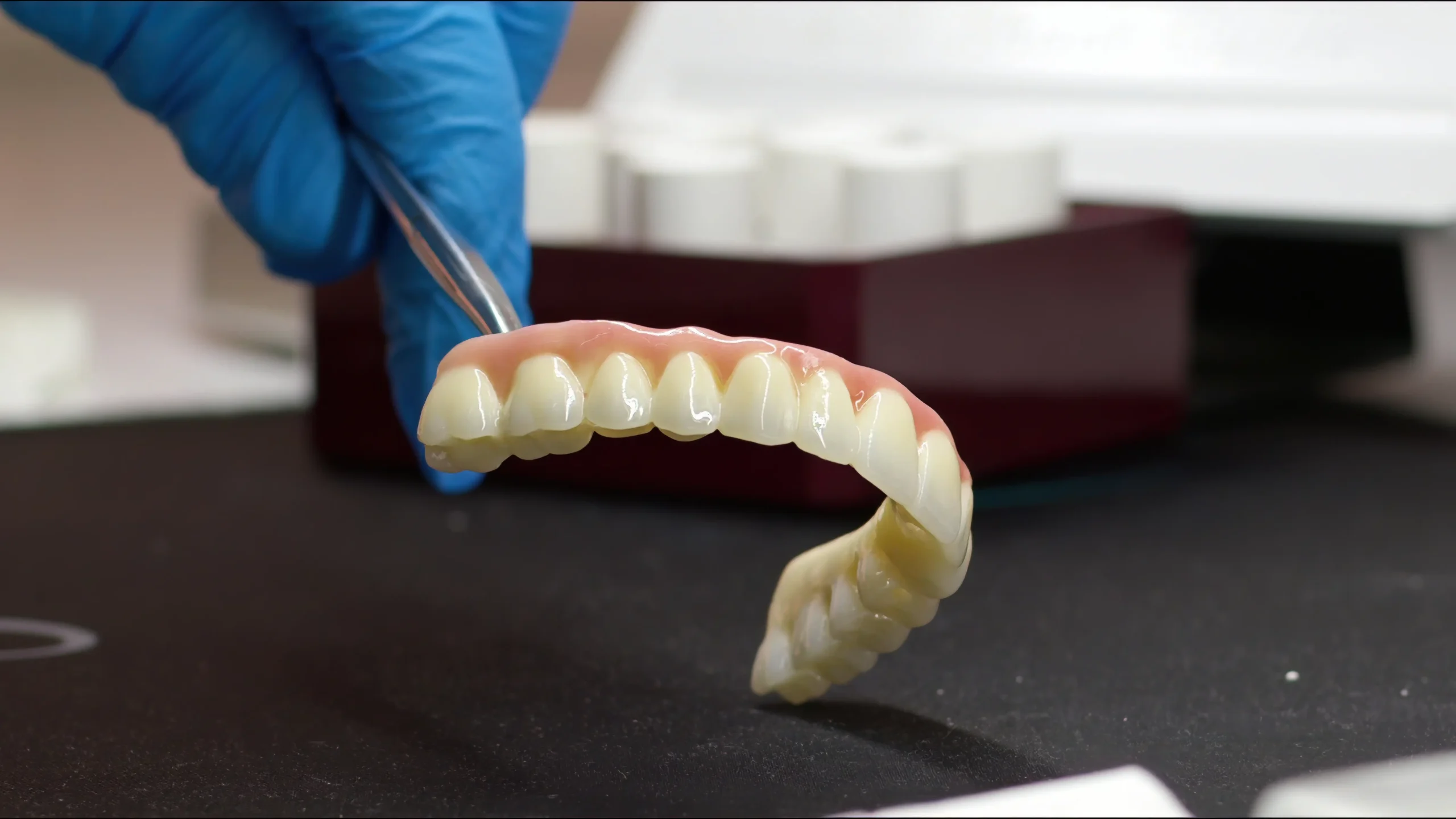 Dental prosthetic held with tweezers in a dental lab