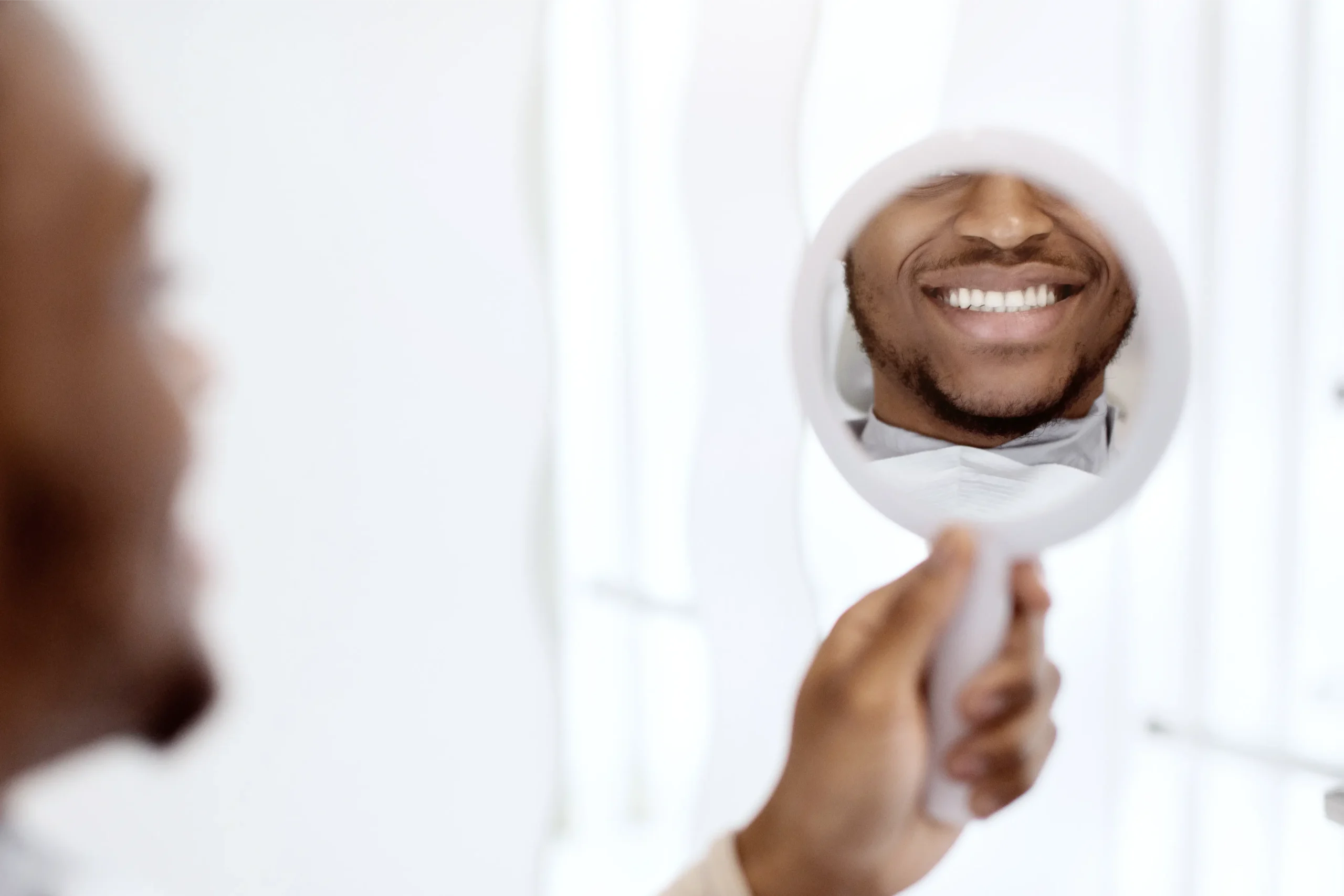 Man admiring his smile in the dentist's mirror
