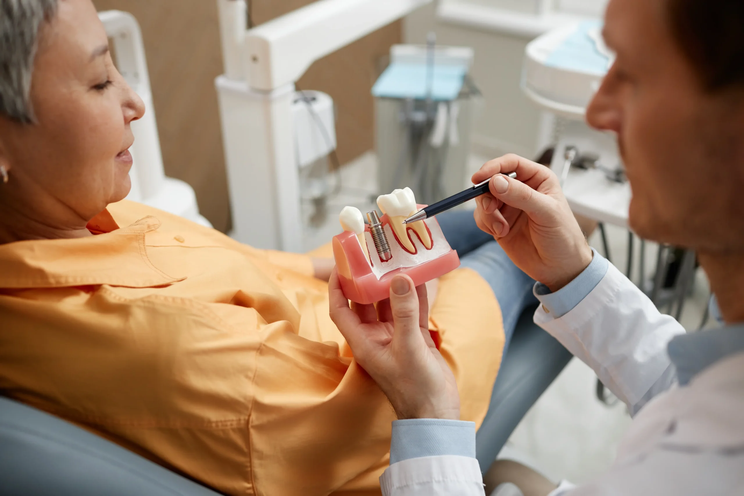 Dentist explaining a dental implant model to a patient