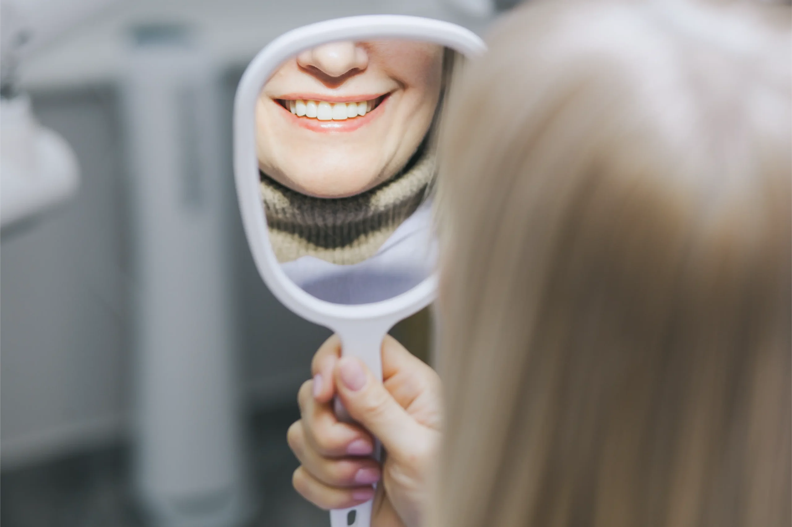 Patient checking her smile in a hand mirror