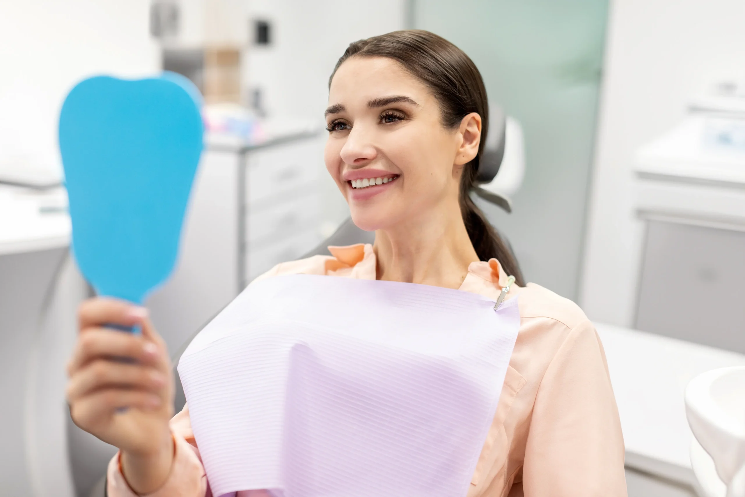 Smiling patient holding a mirror in the dental chair