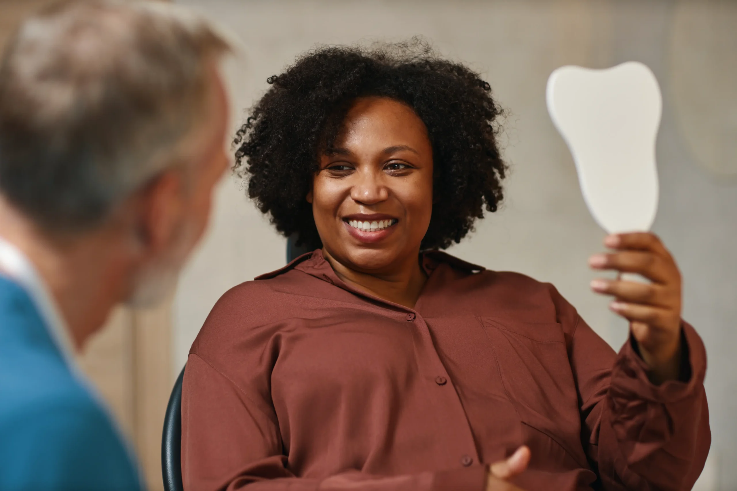 Smiling woman holding a mirror during her dental appointment
