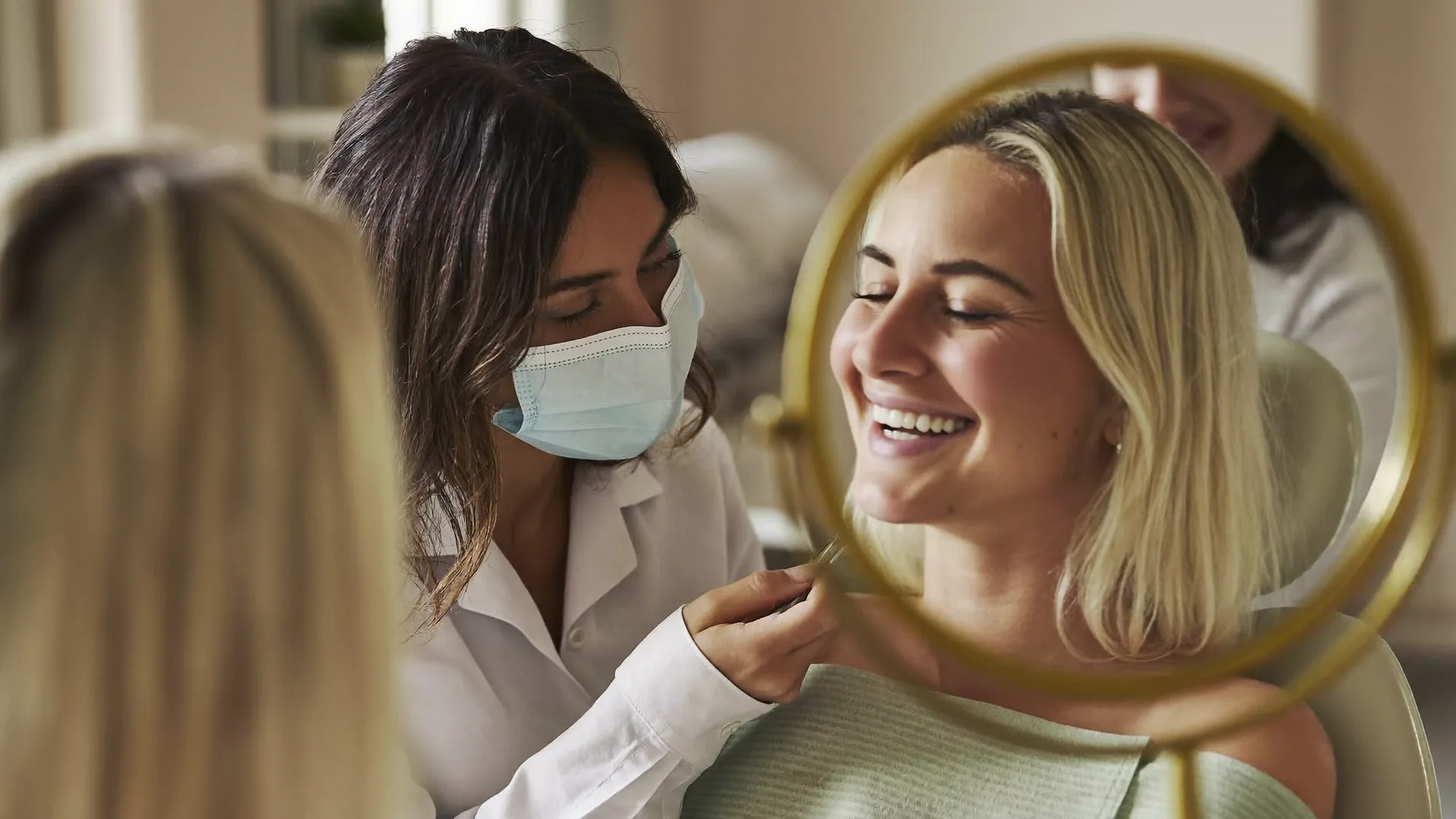 Smiling patient viewing her new smile in a mirror